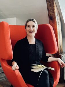 A smiling woman sits in a red chair